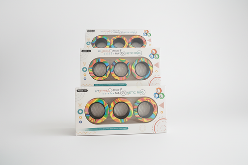 Three packages of a colorful ring product on a wooden surface with a blurred background.