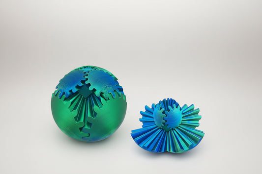 Two green and blue textured 3D gear sphere fidget toy on a white background