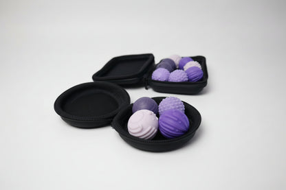 Set of purple and pink textured fidget balls in a black case on a white surface