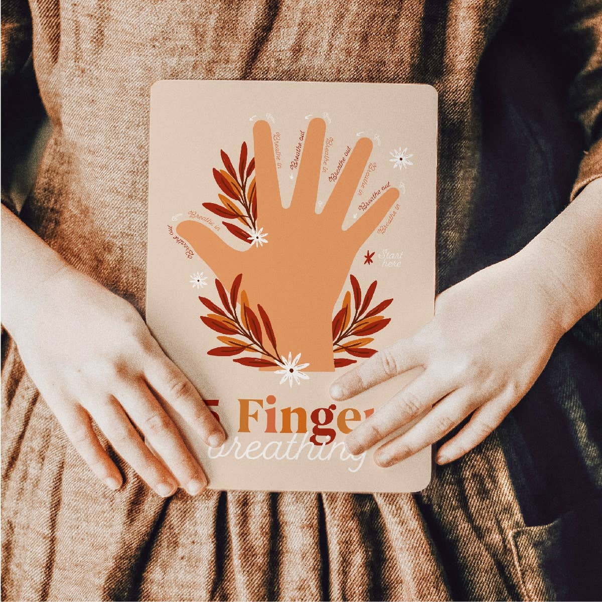Person holding a notebook with a handprint design and 'Finger weaving' text.