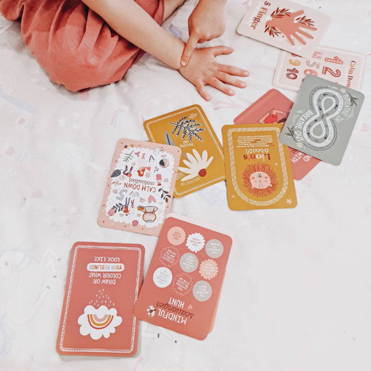 Colorful cards on a light surface with a child's hand reaching towards them