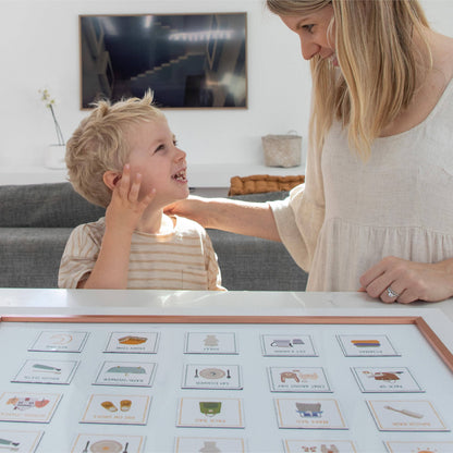 Woman and child interacting with educational cards on a table in a living room.