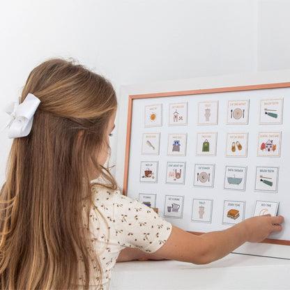 Child interacting with a framed visual schedule on a white wall