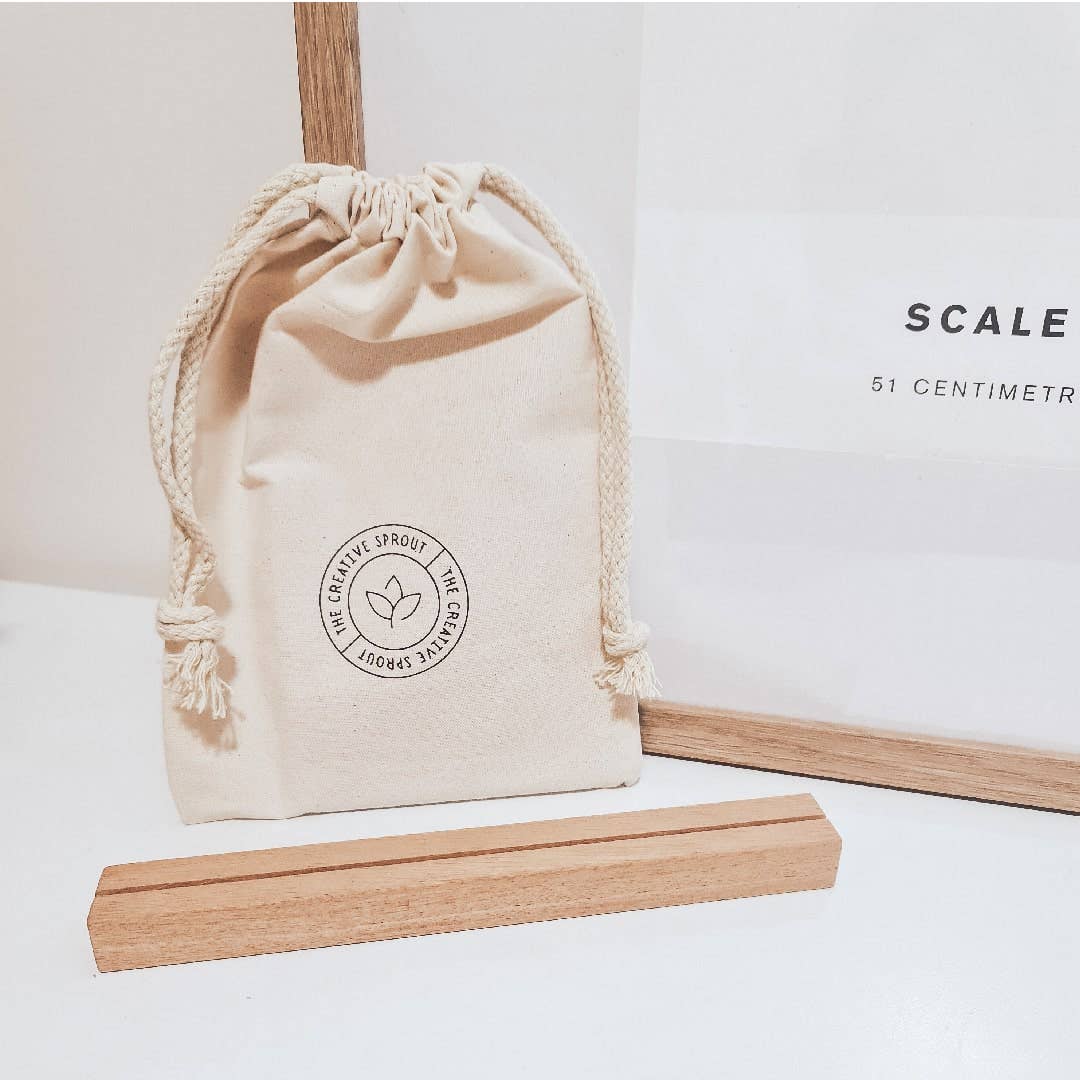 Beige drawstring bag with a logo and wooden sticks on a light background